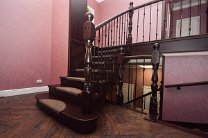 Лестница из ясеня на металлокаркасе с забежными ступенями и кованными балясинами