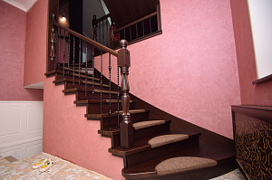 Лестница из ясеня на металлокаркасе с забежными ступенями и кованными балясинами