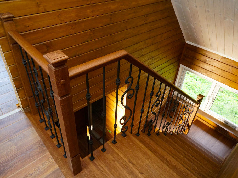 Дубовая межэтажная лестница с художественной ковкой